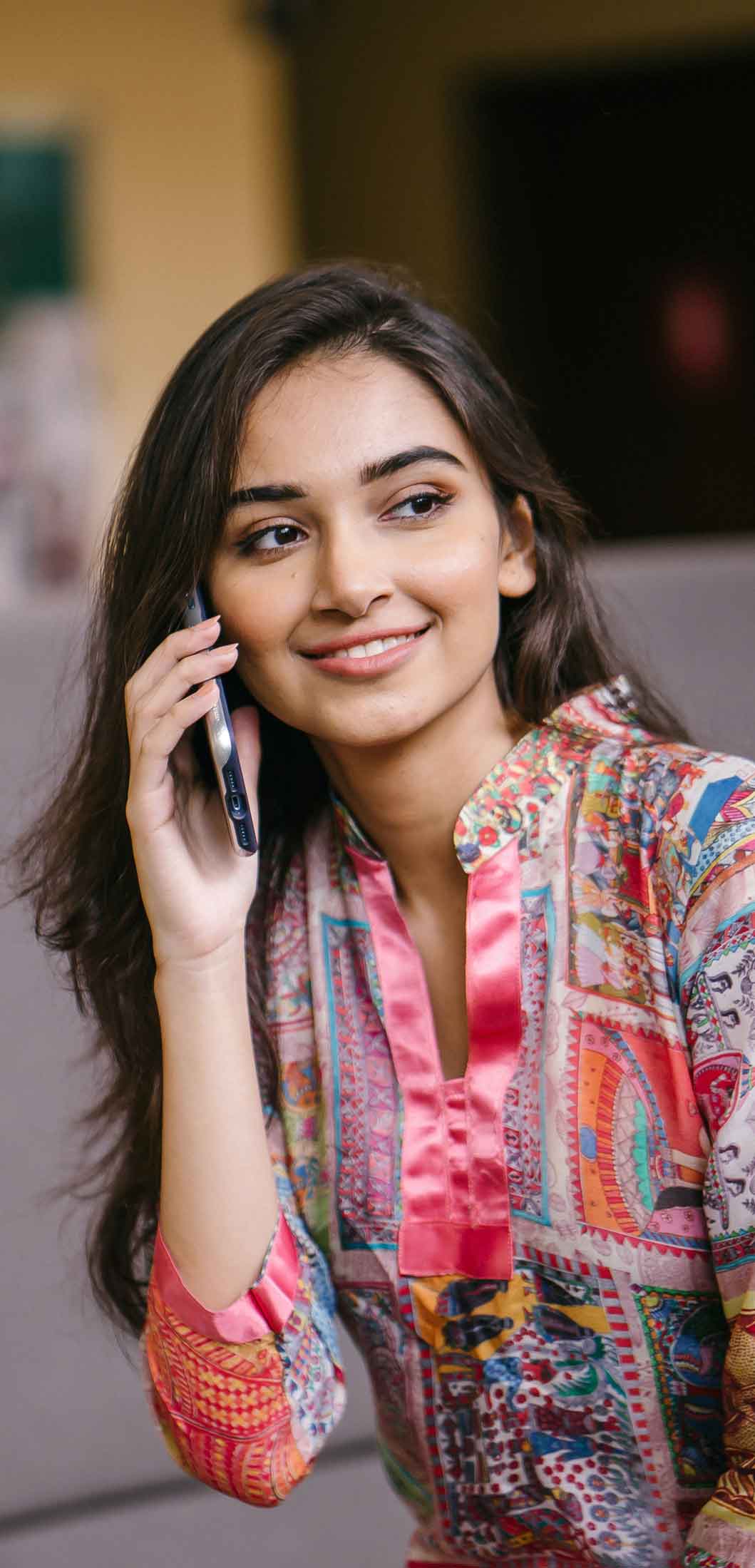 A smiling, attractive young woman on a phone call.